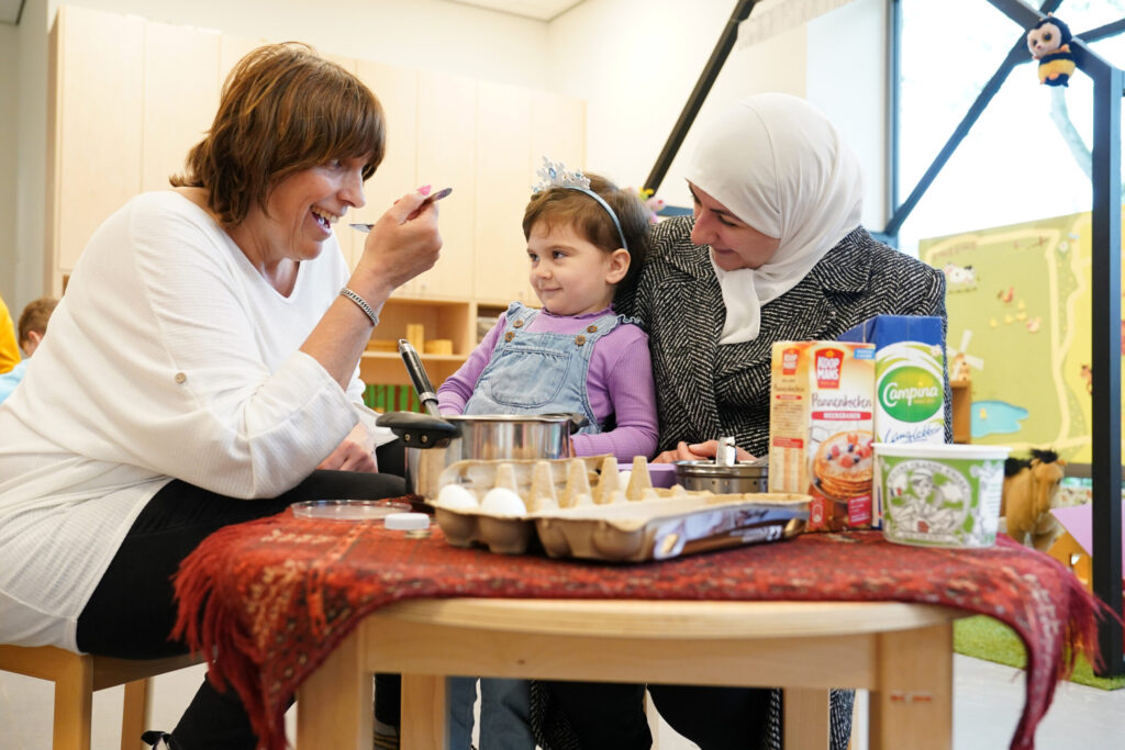 Kind is taart aan het bakken in de klas met twee begeleiders 
