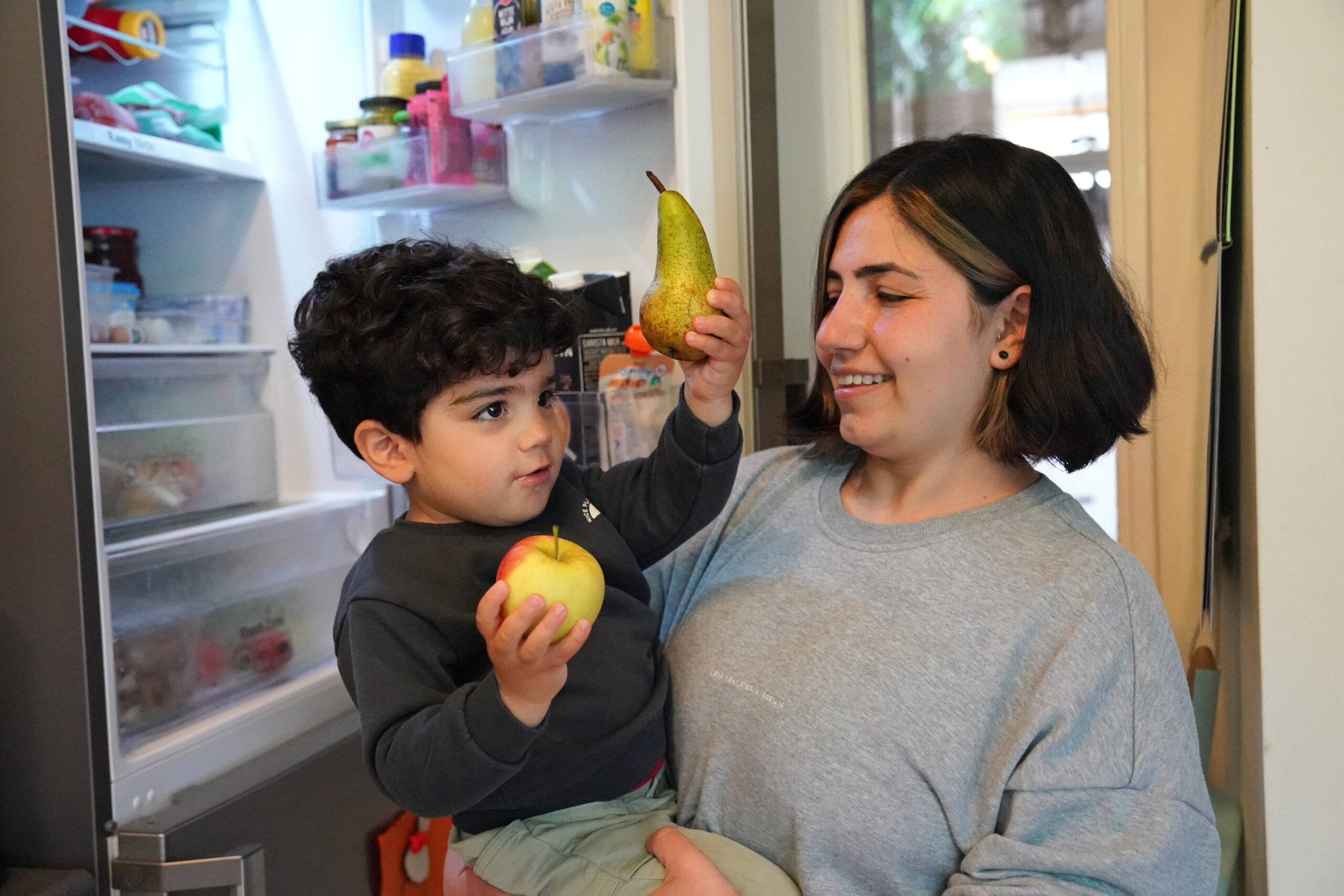 Een kind haalt samen met een begeleider fruit uit een koelkast