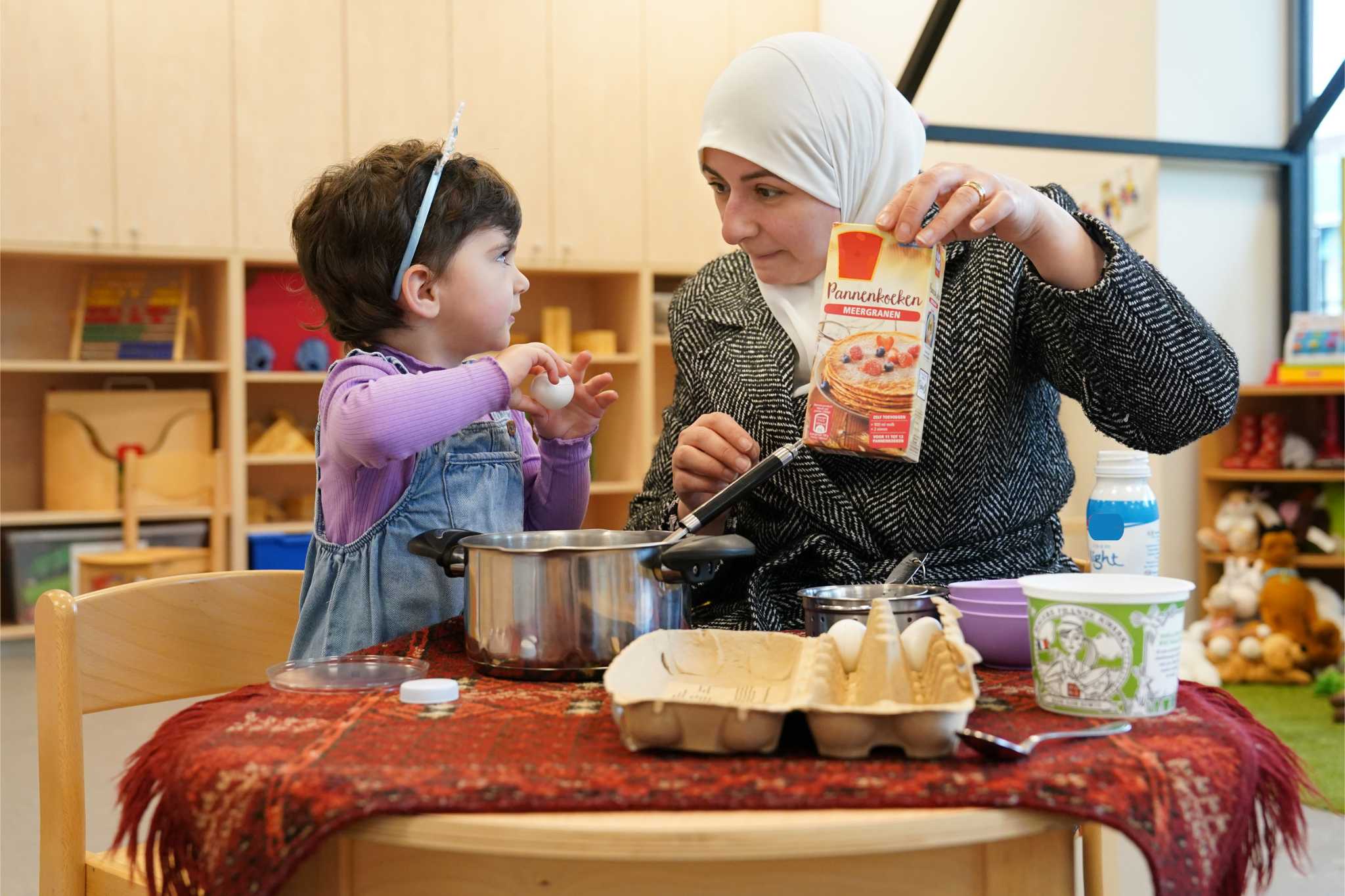 Een kind en begeleider maken samen pannenkoeken