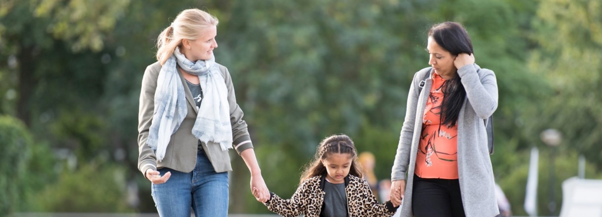 Een kind en twee begeleiders wandelen samen door een park